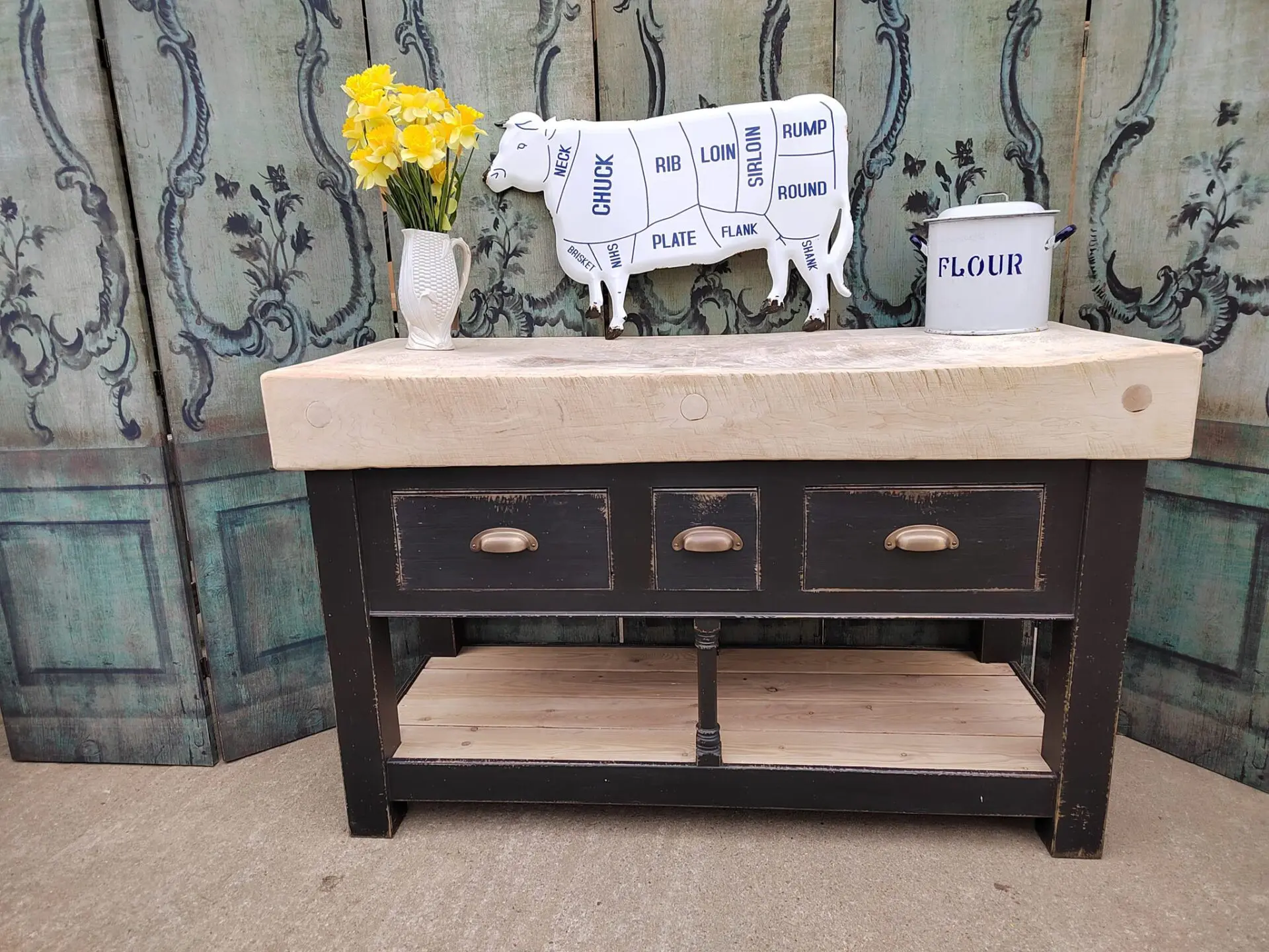 Butcher's block with black base comprised of three drawers and lower shelf.